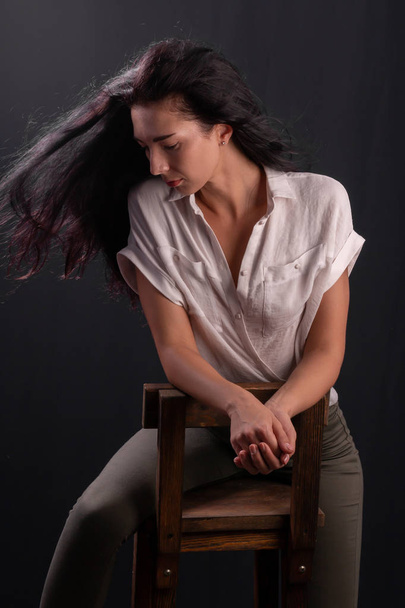 Portrait of young brunette girl is sitting on a chair - Fotó, kép