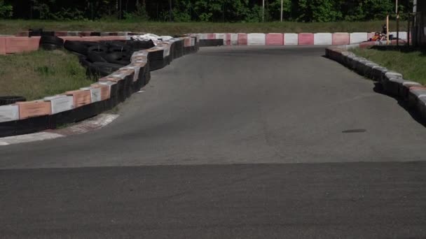 Young racer at go-kart racetrack circuit championship crossing the finish line. Racer with a helmet competing on karting racetrack, fun youth activity - Footage, Video