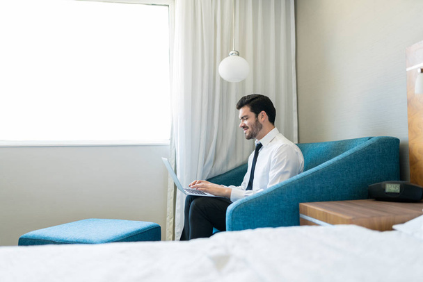 Homme professionnel portant des formals à l'aide d'un ordinateur portable assis sur le canapé à la chambre d'hôtel
 - Photo, image