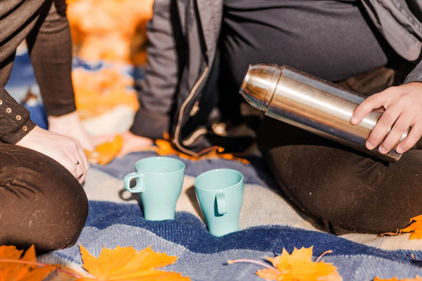 Kochająca Para-mężczyzna i kobieta-spędzają razem w jesiennym parku, pić herbatę z termos - Zdjęcie, obraz