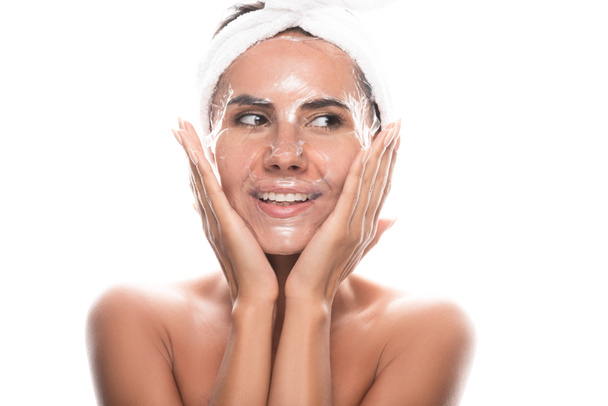 Vooraanzicht van naakte jonge vrouw in cosmetische haarband met gezichtsmasker geïsoleerd op wit - Foto, afbeelding
