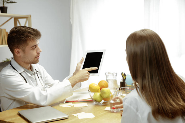 Smiling nutritionist showing a healthy diet plan to patient - Photo, Image