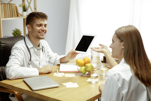 Smiling nutritionist showing a healthy diet plan to patient - Foto, Imagen