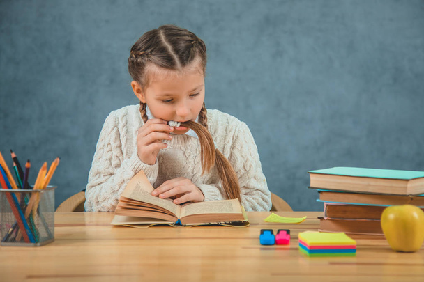 Nice and cute girl is involved in reading. She doesnt have time to eat apple, having her brait in surprised mouth, because there is an interesting story written in the book. - Foto, imagen