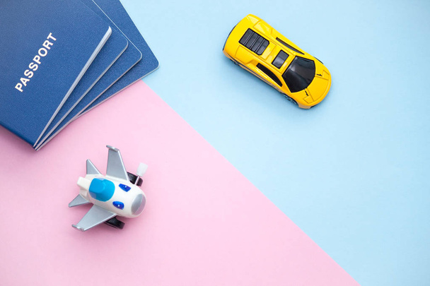 Passaportes, avião e carro sobre fundo rosa e azul celeste. Preparação para o conceito de viagem. Escolha entre carro e avião
. - Foto, Imagem