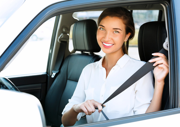 車の中で魅力的な若い女性はシートベルトを締める - 写真・画像
