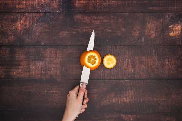 Knife cut the orange on the wooden table  - Photo, Image