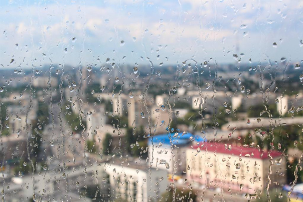 Gocce di pioggia cadono sulla finestra della costruzione contro lo sfondo della torre della città in una giornata di sole
 - Foto, immagini