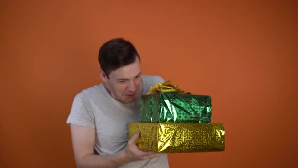 Sad handsome man received a gift and began to dance happily on an orange background. Holiday concept, holiday discounts, gifts and sales. - Filmagem, Vídeo