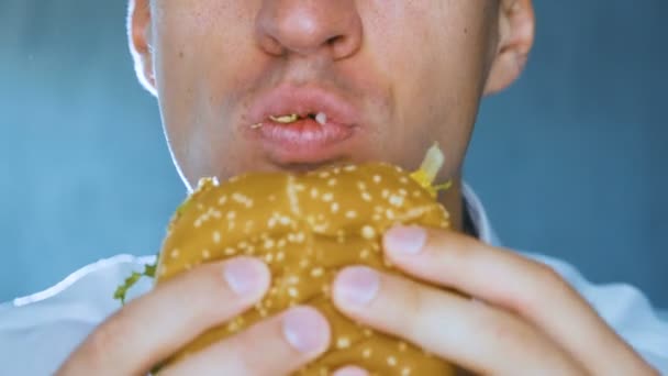 Yakın çekim adam Hamburger yiyor. Hızlı yemek. Cheeseburger, hamburger, sandviç. - Video, Çekim