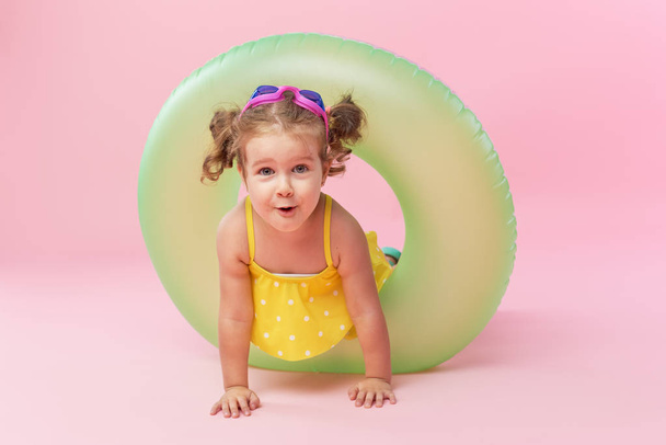 Portrait of happy little girl with neon inflatable rubber circle having fun isolated on pink background - Foto, Imagem