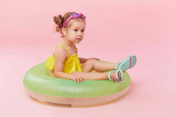 Portrait of happy little girl with neon inflatable rubber circle having fun isolated on pink background - Foto, afbeelding