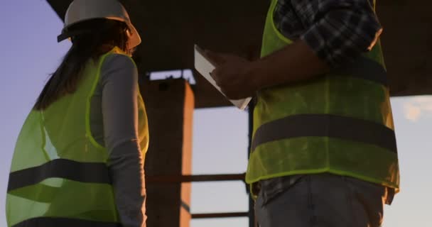 Knappe bouw man en vrouw werknemers in beschermende helmen en vesten schudden handen tijdens het werken in het kantoor centrum. - Video