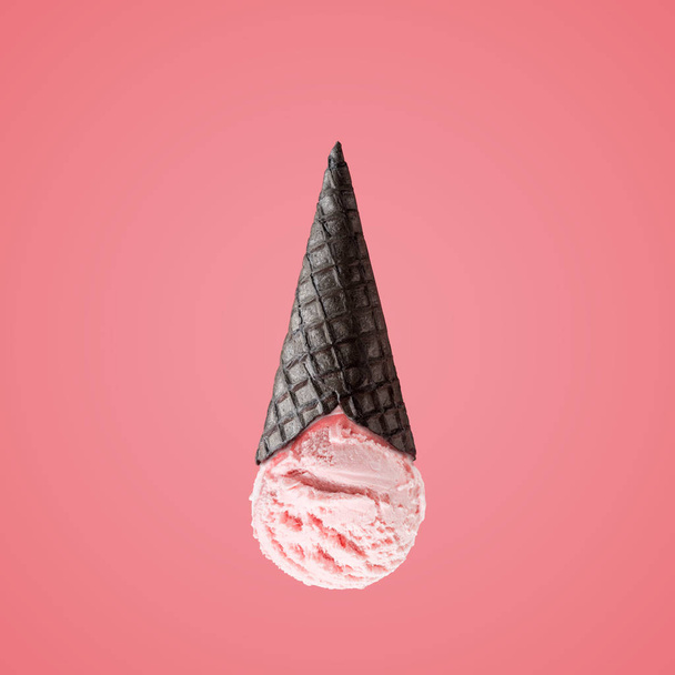 Ice cream scoop with upside down black ice cream cone on bright background. Minimal summer concept. - Фото, изображение