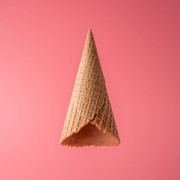 Upside down ice cream cone on bright background. Minimal summer concept. - Foto, imagen