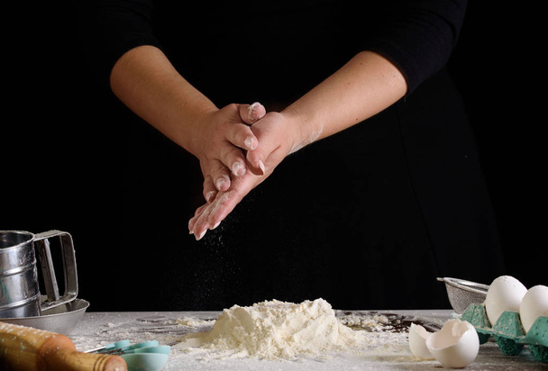 The cooking process, hands on a black background, flour. Confectioner - Photo, Image