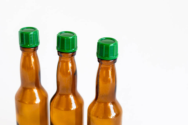 Close-up corner shoot of three line positioned small alcohol bottles brown colored - Foto, Imagen
