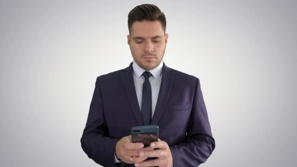 Serious businessman texting message on his phone on gradient background. - Video