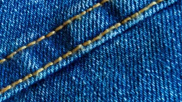 Tessuto in denim o cotone grezzo o materiale jeans con la cucitura cucita per lo sfondo testurizzato tessile di colore blu pallido. Macro filmato girato
 - Filmati, video