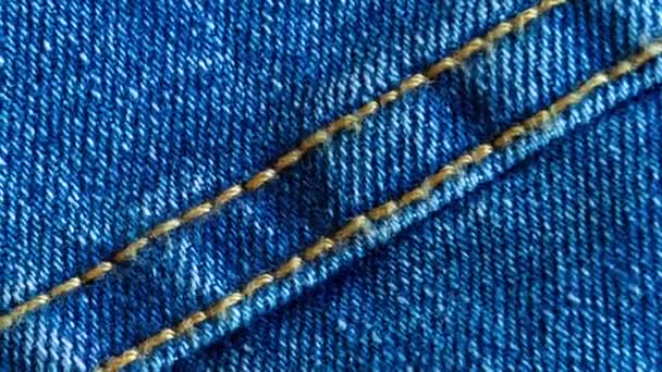 Denim or rough cotton fabric or jeans material with the stitched seam for the textile textured background of pale blue color. Macro shot footage - Footage, Video