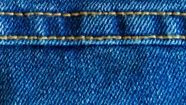 Denim or rough cotton fabric or jeans material with the stitched seam for the textile textured background of pale blue color. Macro shot footage - Footage, Video