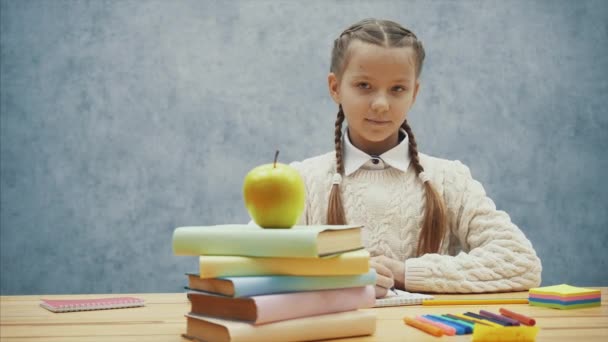 Schoolgirl stops writing and smells tasty yellow apple. - Imágenes, Vídeo