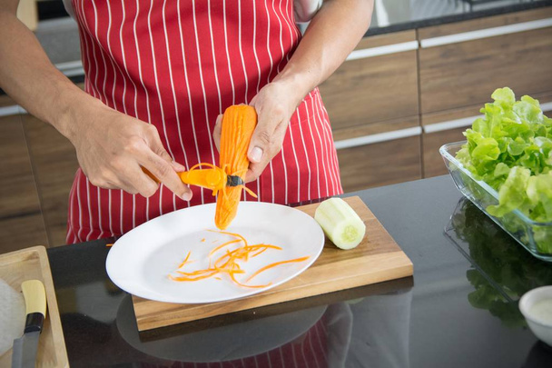 Le chef professionnel aux mains rugueuses pour râper les carottes à préparer
 - Photo, image