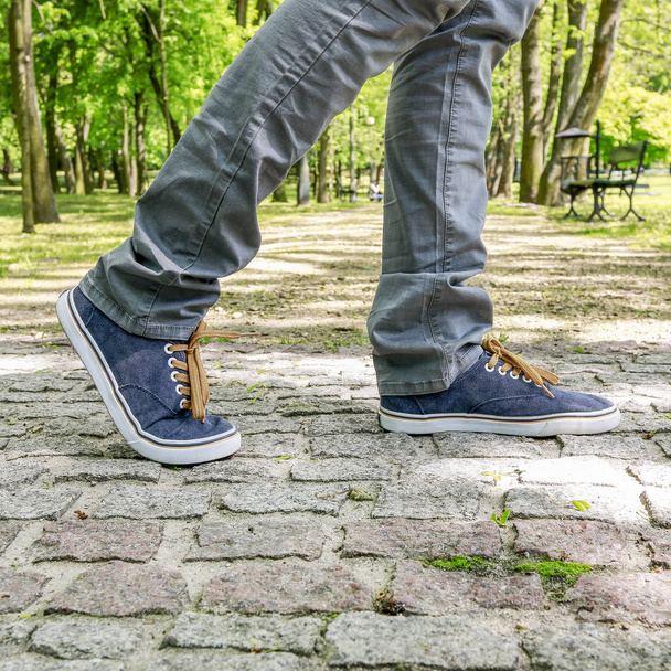 Young person wearing sneakers, walking on the cobbled street. - Photo, Image