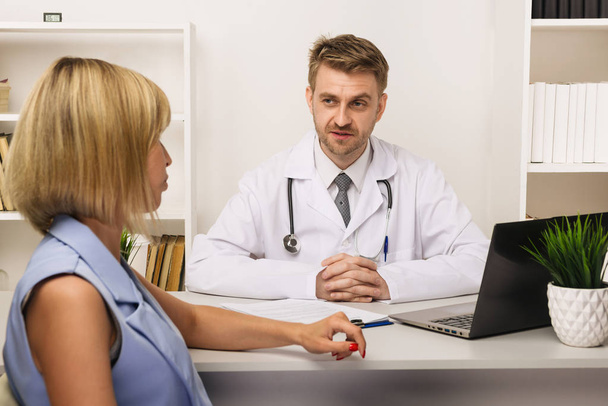 Young woman on a consultation with a male surgeon or therapist in his office. - Photo, Image