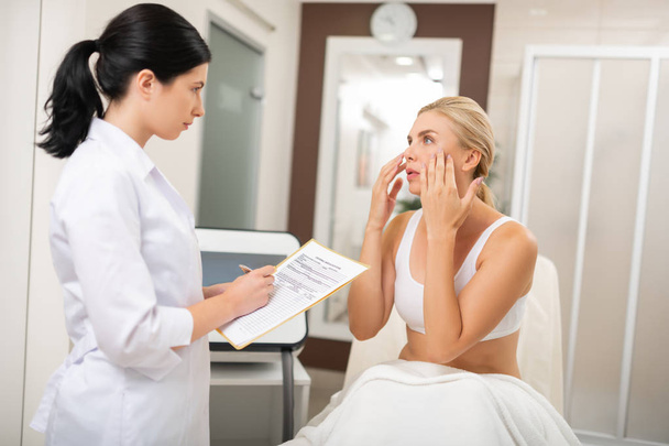 Woman telling a beauty doctor about needed procedures. - Fotó, kép
