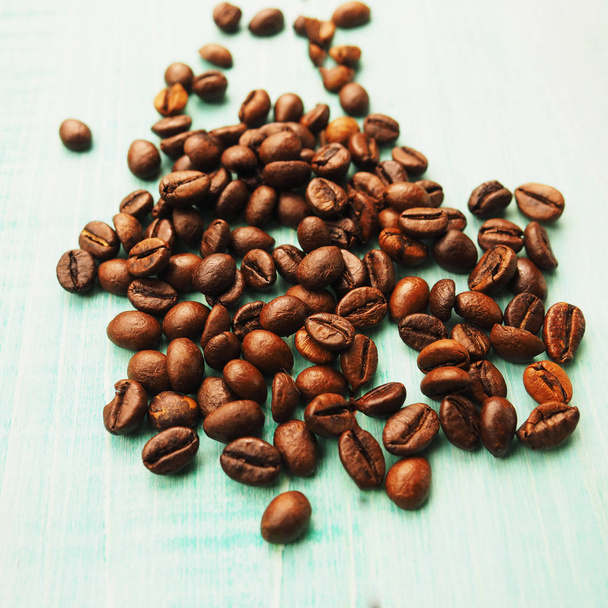 青い木製の背景、正方形のフォーマットのコーヒー豆の一握り - 写真・画像