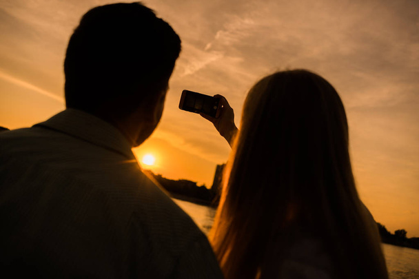 Happy couple is photographing sunset in the city.  - Foto, imagen