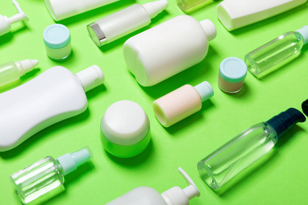 Close-up set of diffrent sized bottles and jars for cosmetic products on green backgound. Face and body care concept with copy space - Foto, Bild