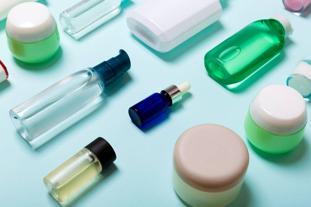 Top uitzicht van cosmetische producten in verschillende potten en flessen op blauwe achtergrond. Close-up van containers met Kopieer ruimte - Foto, afbeelding