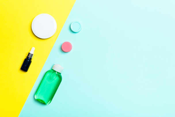 Ansicht von Kosmetikbehältern, Sprays, Dosen und Flaschen auf gelbem und blauem Hintergrund. Nahsicht mit leerem Raum für Ihr Design - Foto, Bild