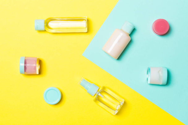 黄色と青の背景に化粧品容器、スプレー、瓶やボトルのトップビュー。デザインのための空きスペースを持つクローズアップビュー - 写真・画像