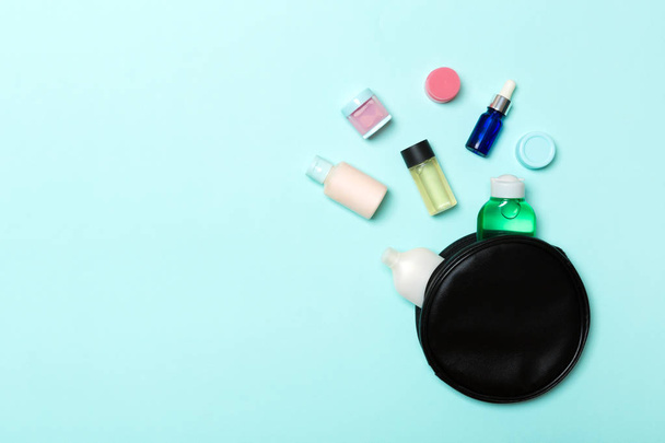 Group of beauty cream bottles dropped out of the cosmetics bag on blue background. Space for your design. Top view of skincare concept - Photo, Image