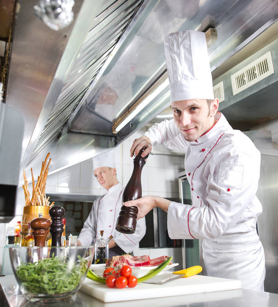 The chef prepares a dish in the kitchen of restoran - Valokuva, kuva