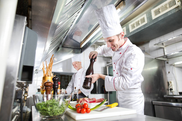 The chef prepares a dish in the kitchen of restoran. - Foto, Bild