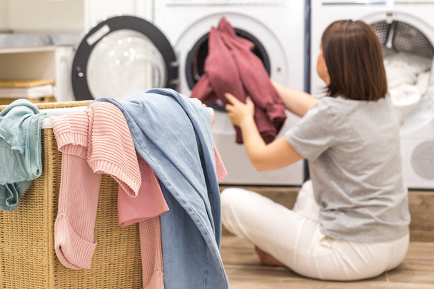 Frau lädt schmutzige Wäsche in Waschmaschine zum Waschen in modernen Hauswirtschaftsraum - Foto, Bild