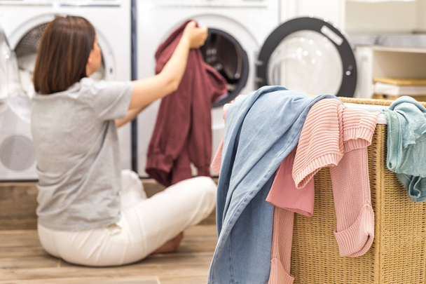 Frau lädt schmutzige Wäsche in Waschmaschine zum Waschen in modernen Hauswirtschaftsraum - Foto, Bild