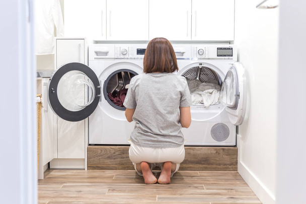 Mujer cargando ropa sucia en la lavadora para lavar en el cuarto de servicio moderno
 - Foto, imagen