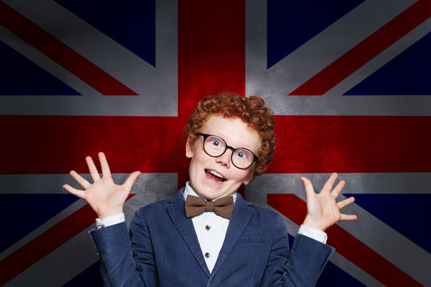 Funny mischievous child boy student against the UK flag background - Photo, Image