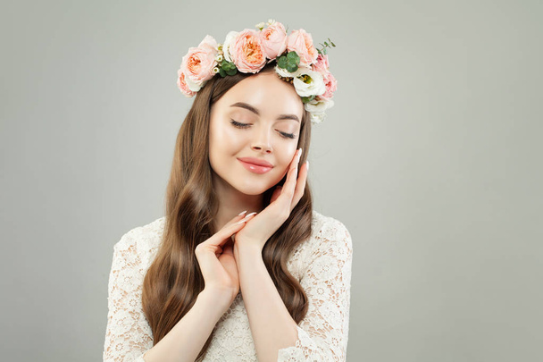 niedliche Frau mit klarer Haut, langen, glänzenden Haaren und Blumen entspannend - Foto, Bild