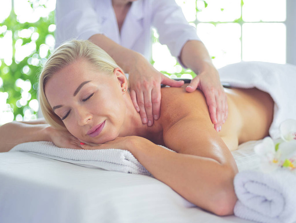 Beautiful spa woman lying on towel in spa salon - 写真・画像