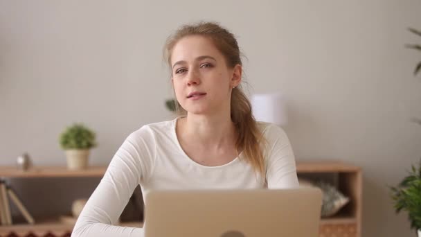 Positive girl sitting at desk speaks to camera motivational speech - Záběry, video
