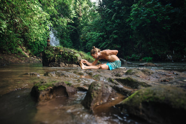 Yoga practice and meditation in nature. Man practicing near river - Foto, Bild