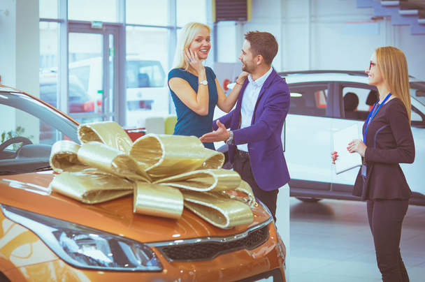 A man makes a gift - a car to his wife. She is surprised at this. They are very happy about this - Foto, Imagen