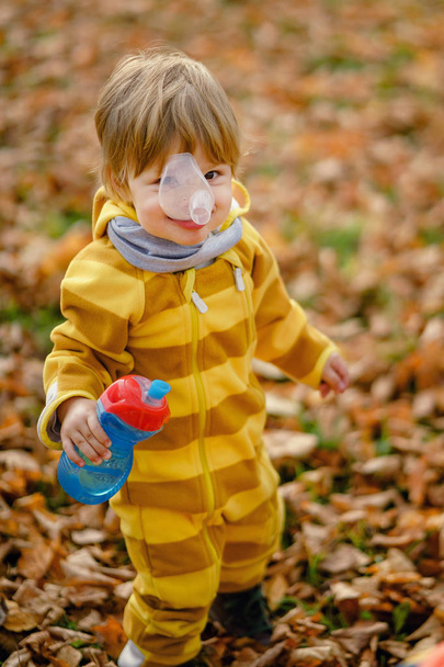 Happy little boy with water bottle playing in the autumn on the walk at park - Photo, Image