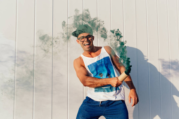 Cheerful guy playing with smoke flare outdoors. - Foto, imagen
